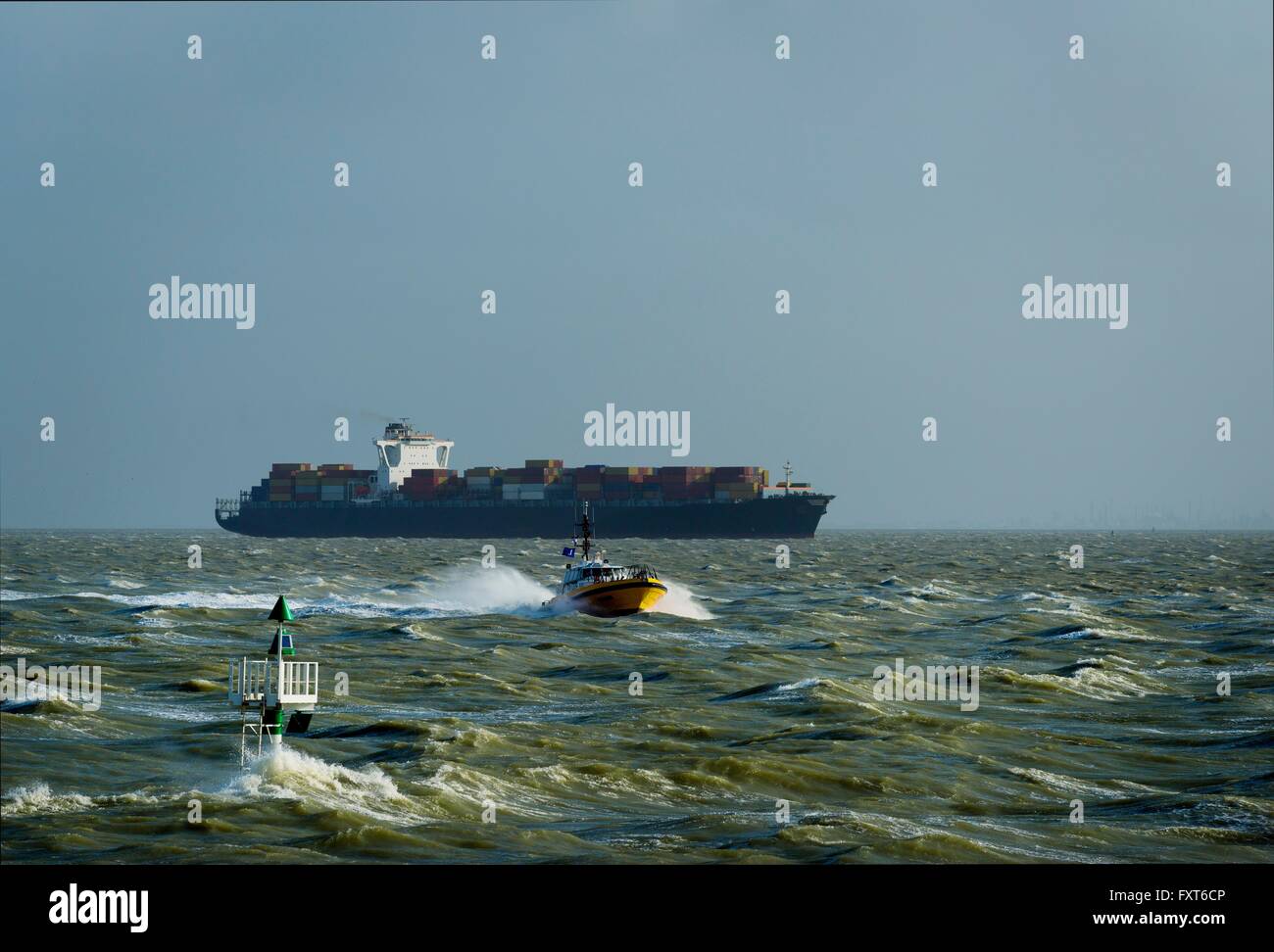 Container ship sailing Westerschelde river, towards open sea, after visiting Antwerp harbour. Pilot collected by pilots boat Stock Photo