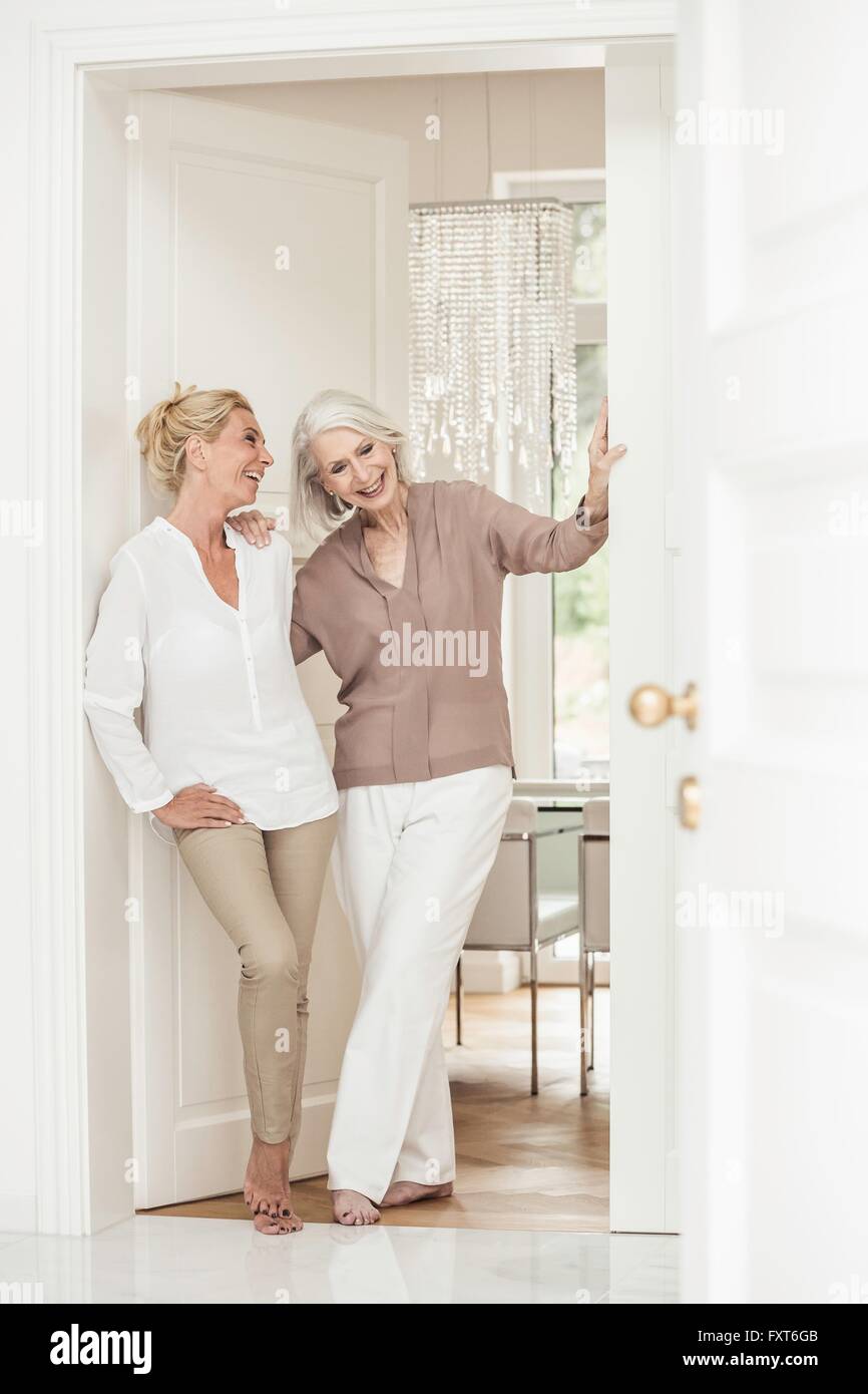 Mother and daughter standing together at home, laughing Stock Photo