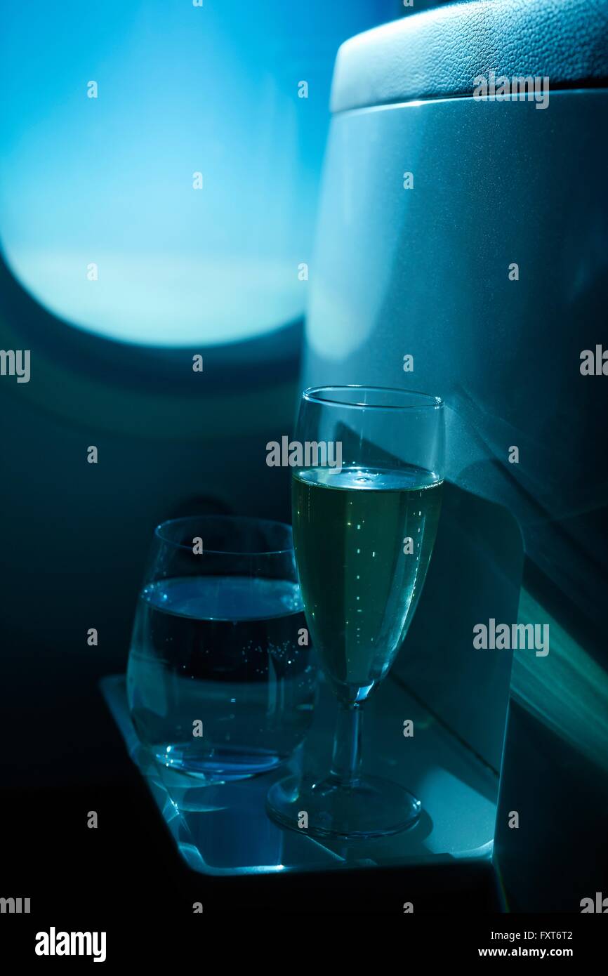 Champagne flute and tumbler in front of airplane window Stock Photo