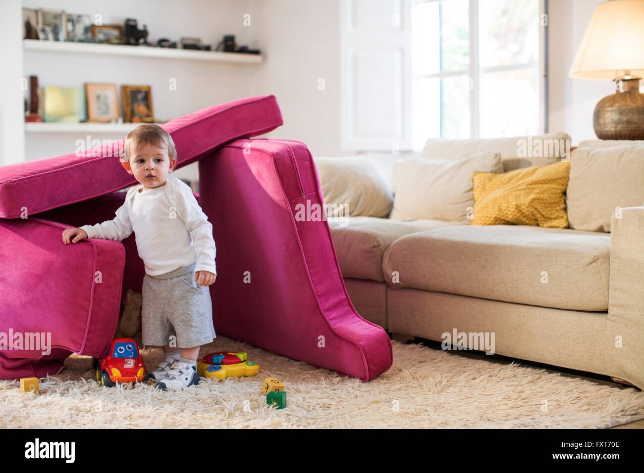 Baby boy playing in fort made from sofa cushions Stock Photo