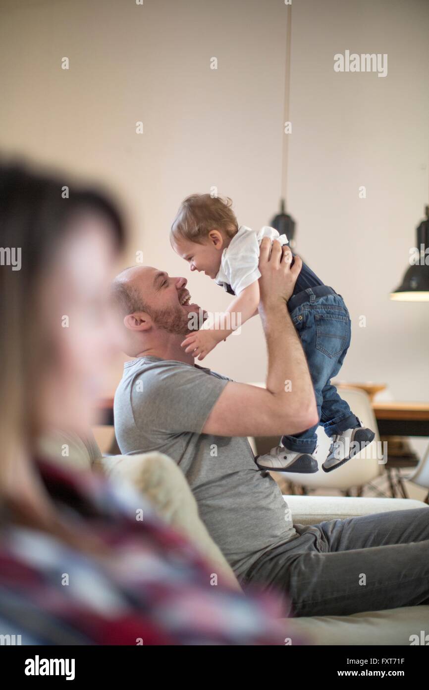 Father lifting up baby boy face to face smiling Stock Photo