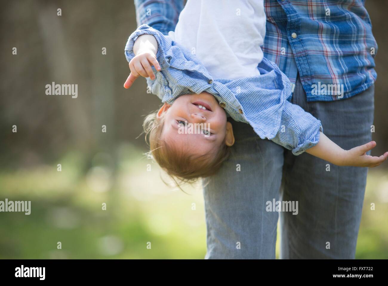 Low section of father hanging smiling baby boy upside down Stock Photo