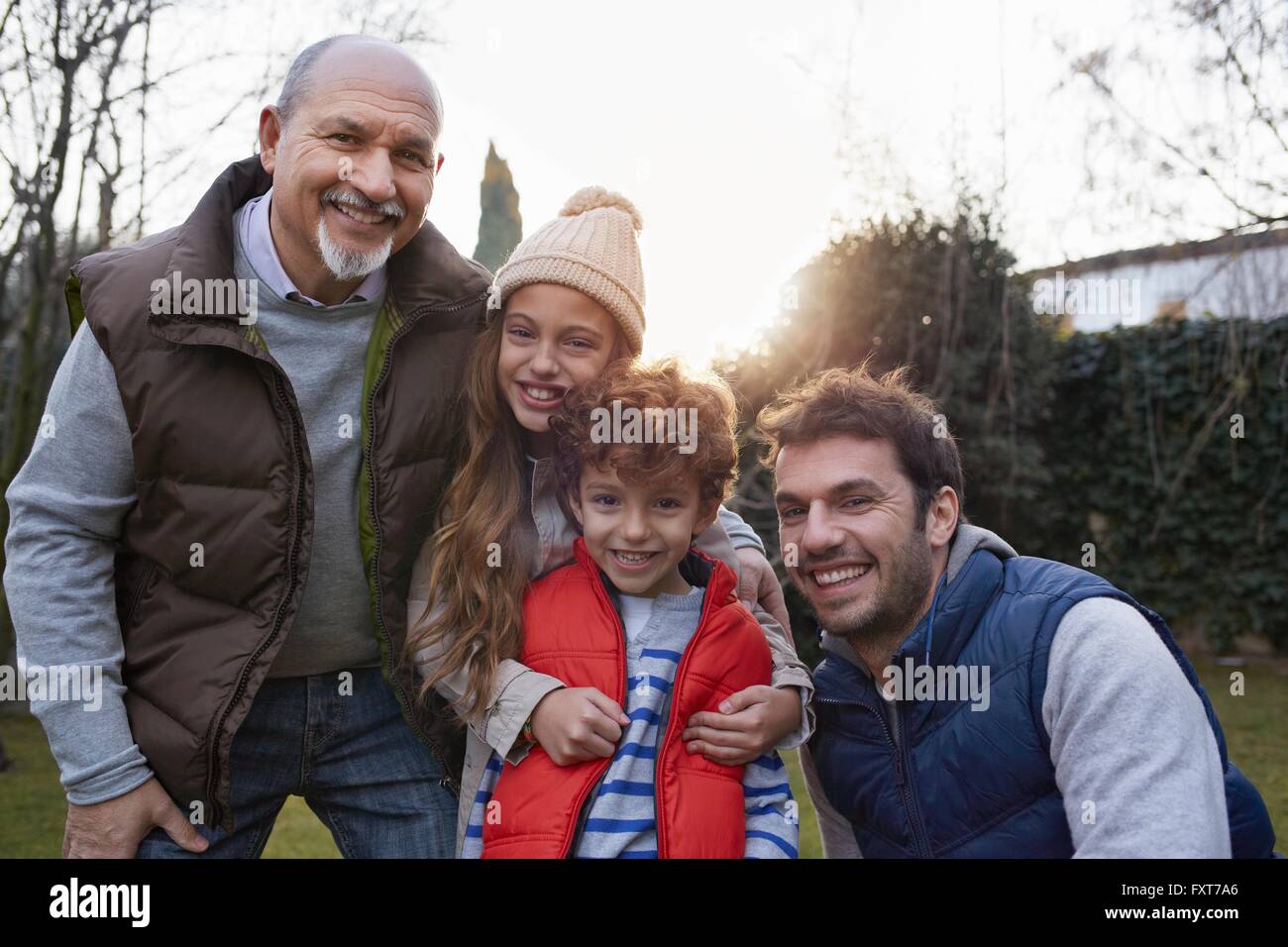 Multi generation family huddled together looking at camera smiling Stock Photo