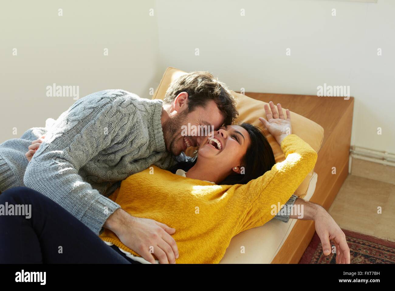 Mid adult couple on window seat face to face laughing Stock Photo