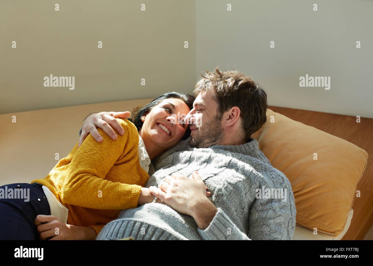 Mid adult couple on window seat face to face laughing Stock Photo