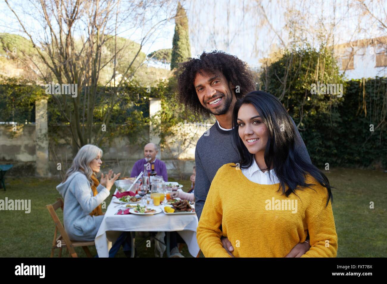 Couple in garden dining with family looking at camera smiling Stock Photo