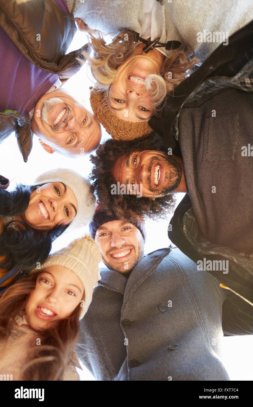 Multi generational family in a huddle bending forward looking down at camera smiling Stock Photo