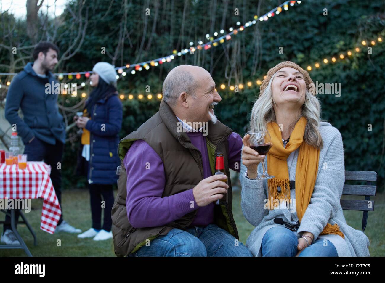 Mature couple at garden party throwing head back laughing Stock Photo