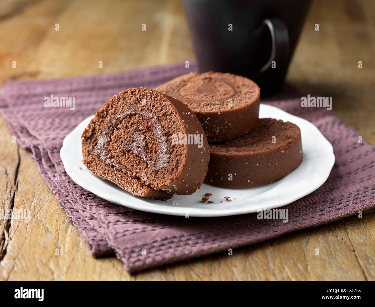 Chocolate sponge roll, purple napkin Stock Photo