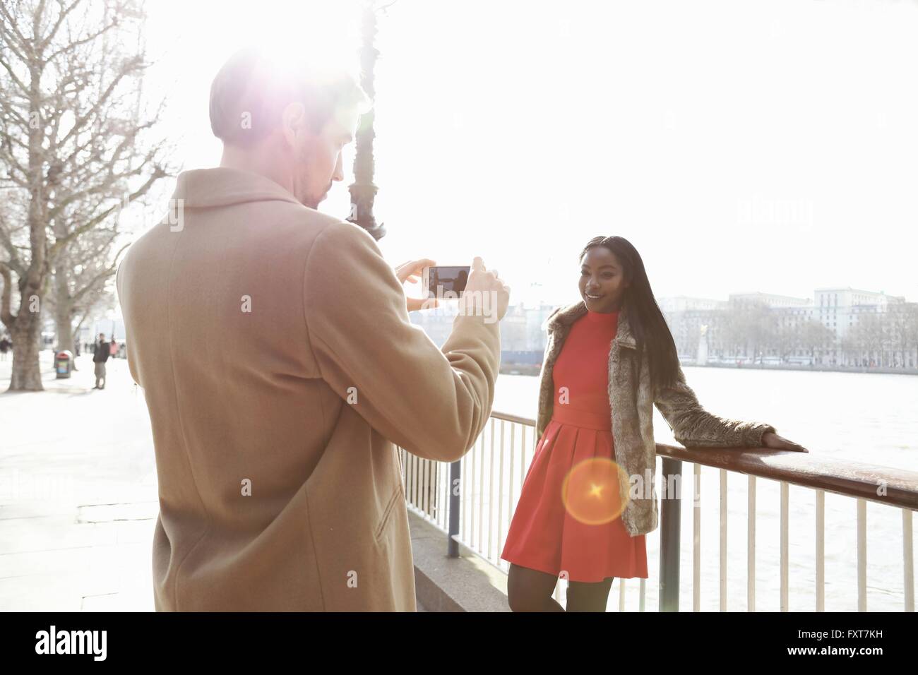 Couple standing beside river, young woman leaning against railings, man ...
