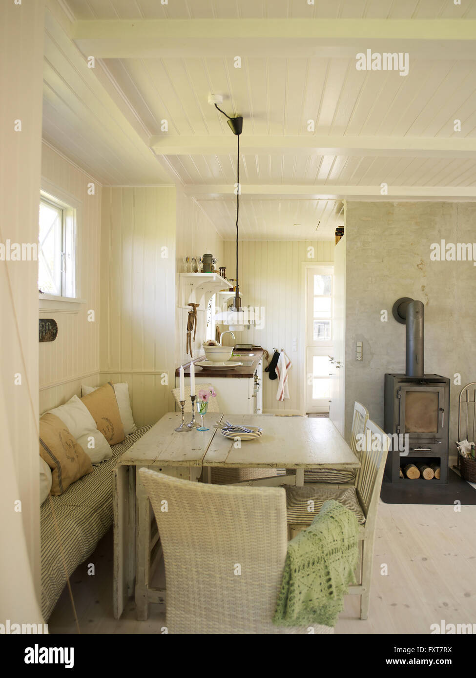 White panelled living room with dining table and wood burner Stock Photo