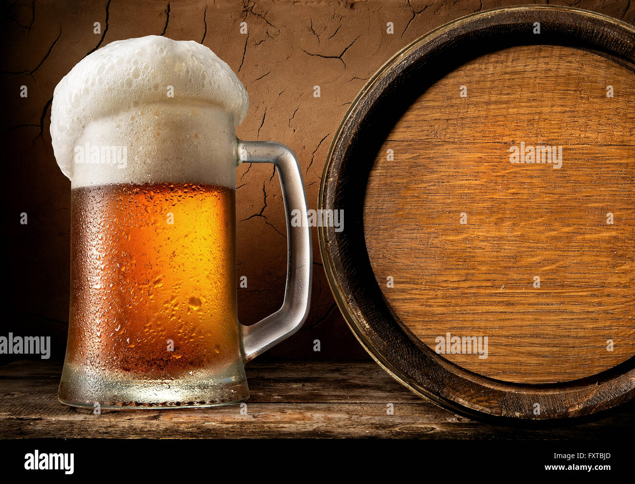 Frothy beer and wooden barrel in clay cellar Stock Photo