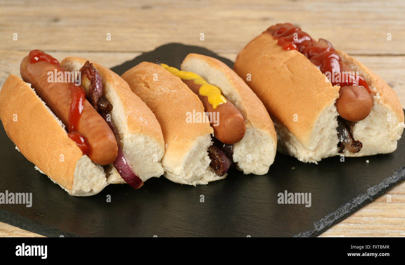 Three hot dogs on bread rolls with mustard and ketchup Stock Photo