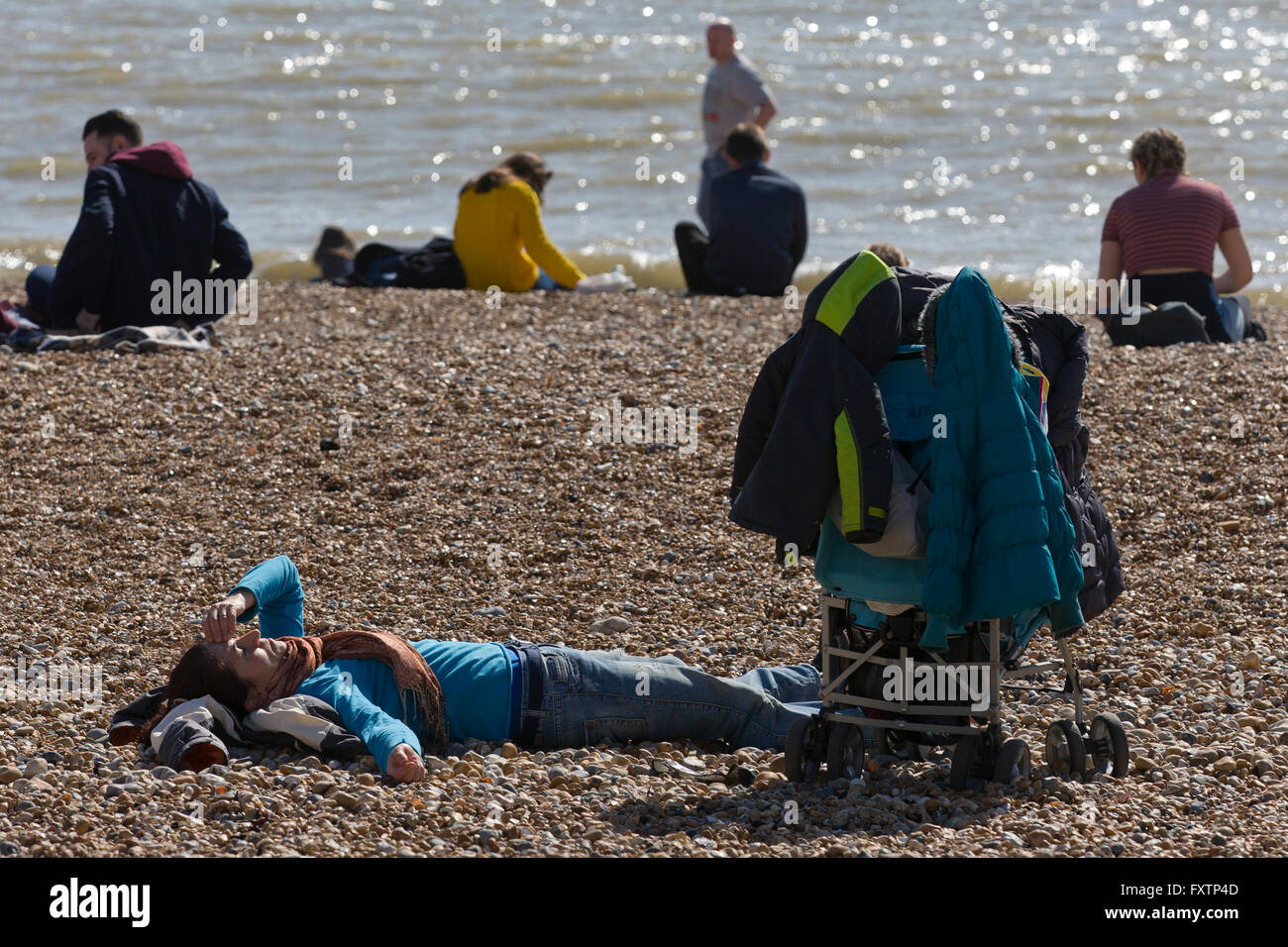 A person has a rest on Brighton beech next to their pram. March 2016. Stock Photo