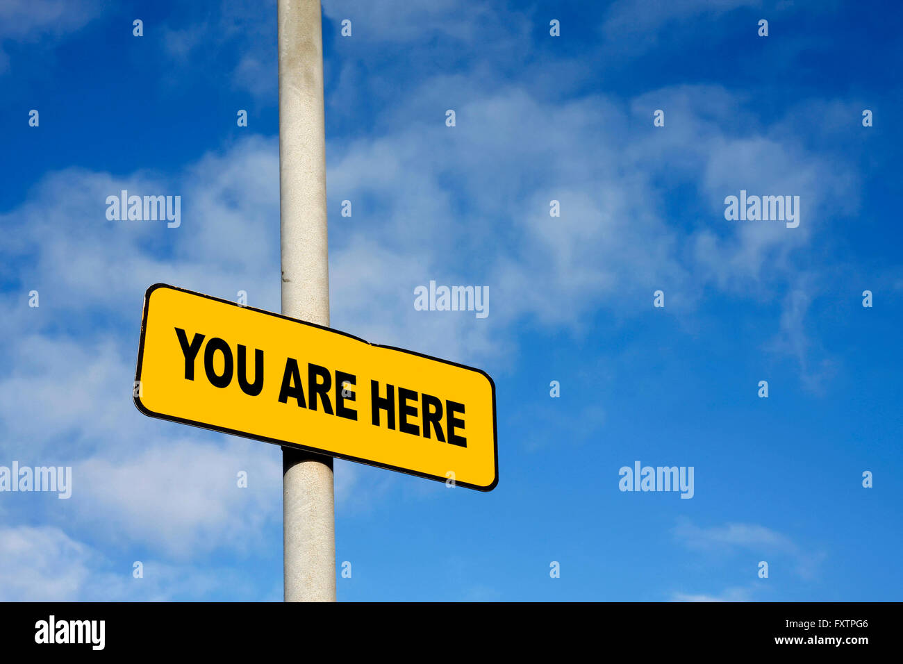 Yellow You Are Here sign against a blue sky Stock Photo - Alamy