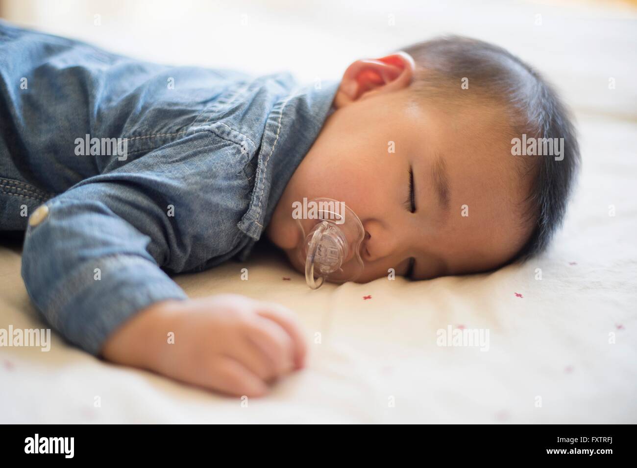 Baby boy with pacifier sleeping on bed Stock Photo Alamy