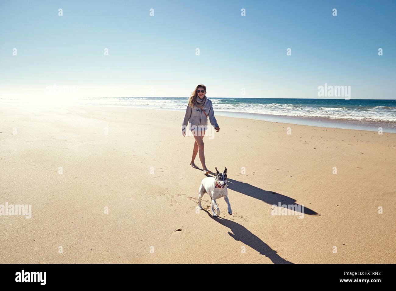 Mature woman with running dog on beach, Conil de la Frontera, Spain Stock Photo