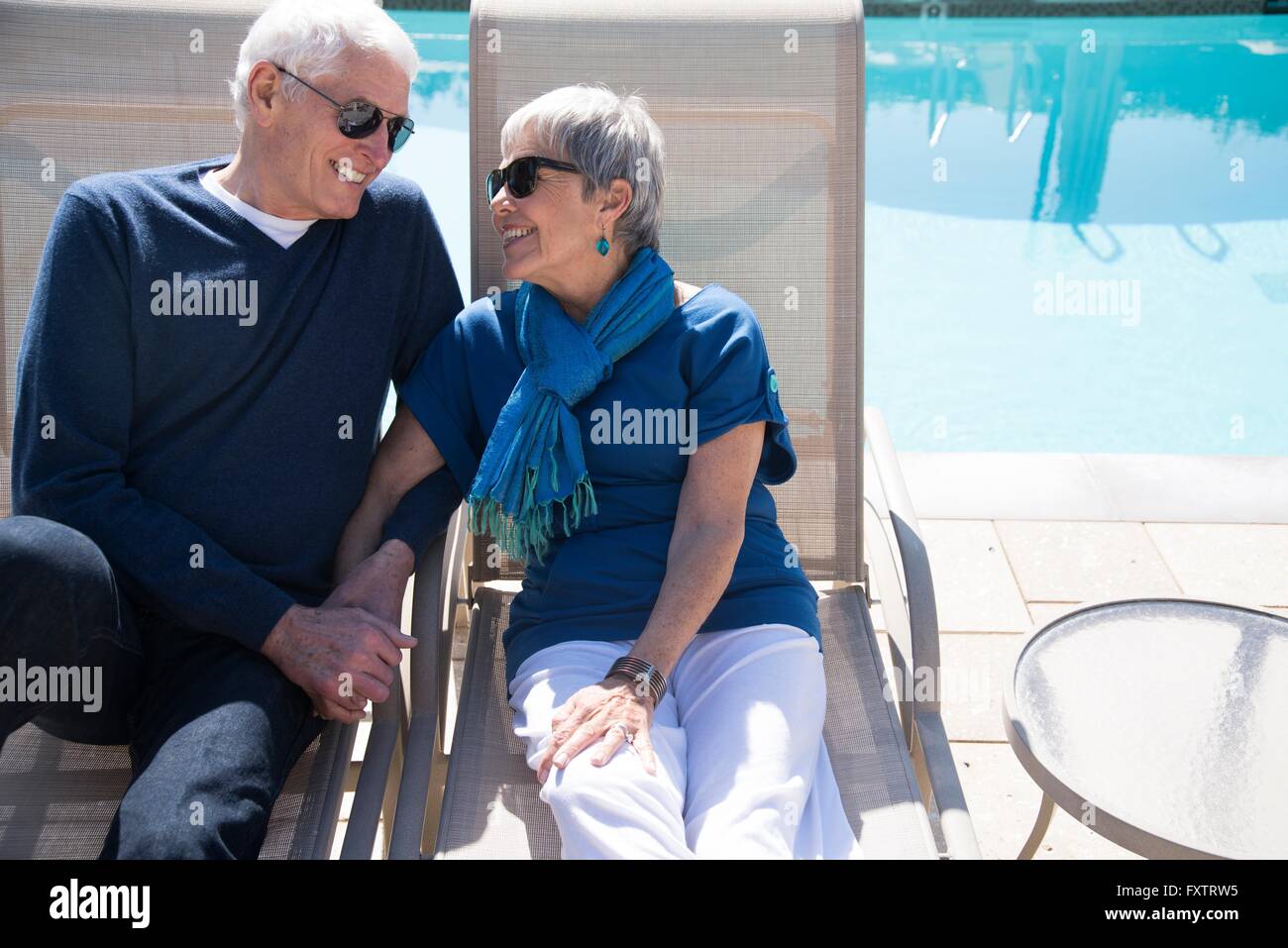 Senior couple relaxing on sun loungers beside pool Stock Photo - Alamy