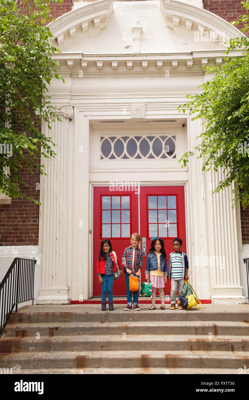 Portrait of four boys and girls standing elementary school entrance Stock Photo