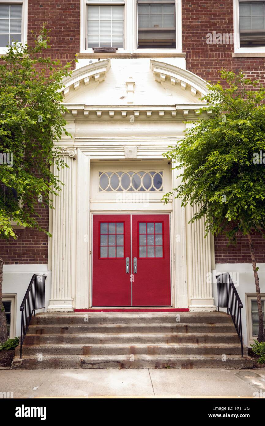 Stairway entrance to traditional elementary school with red door Stock Photo