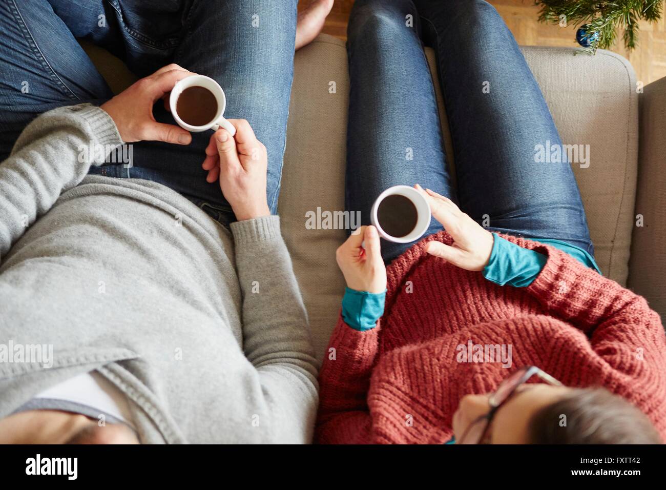 Overhead view of couple sitting on sofa holding coffee cup Stock Photo