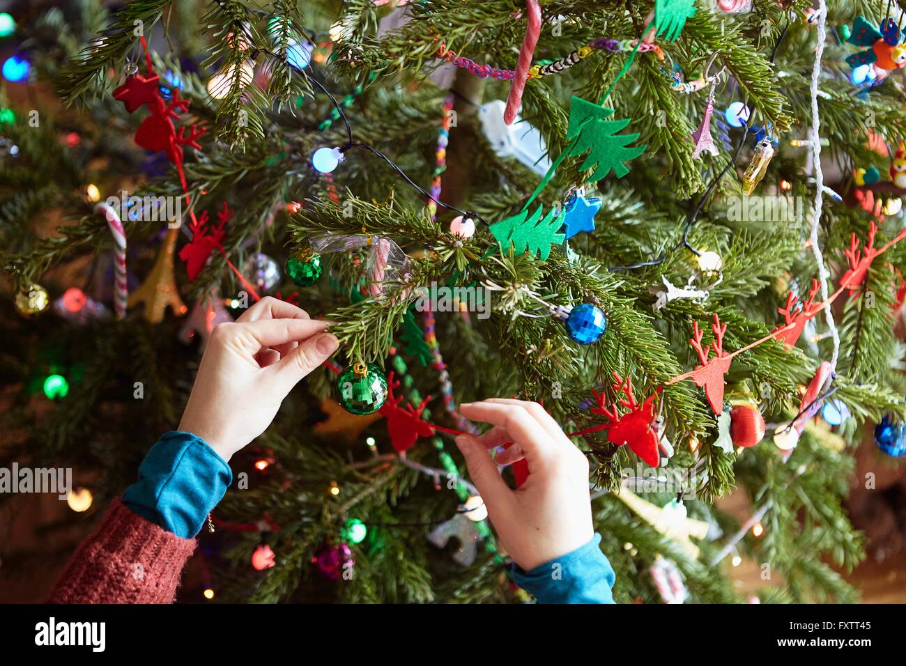 Womans hands preparing xmas decorations on xmas tree Stock Photo