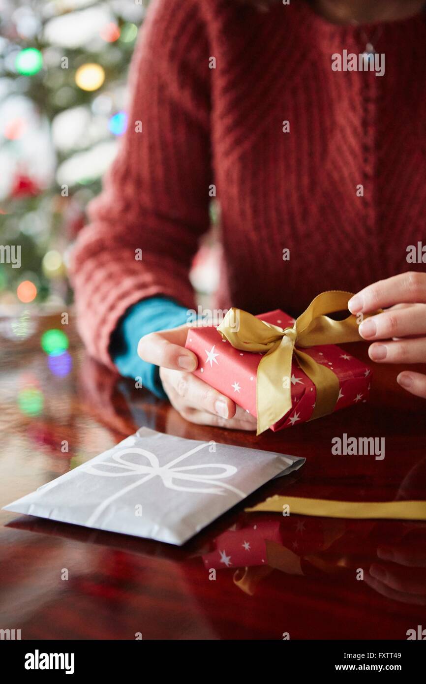 Close up of womans hands wrapping xmas gift at table Stock Photo