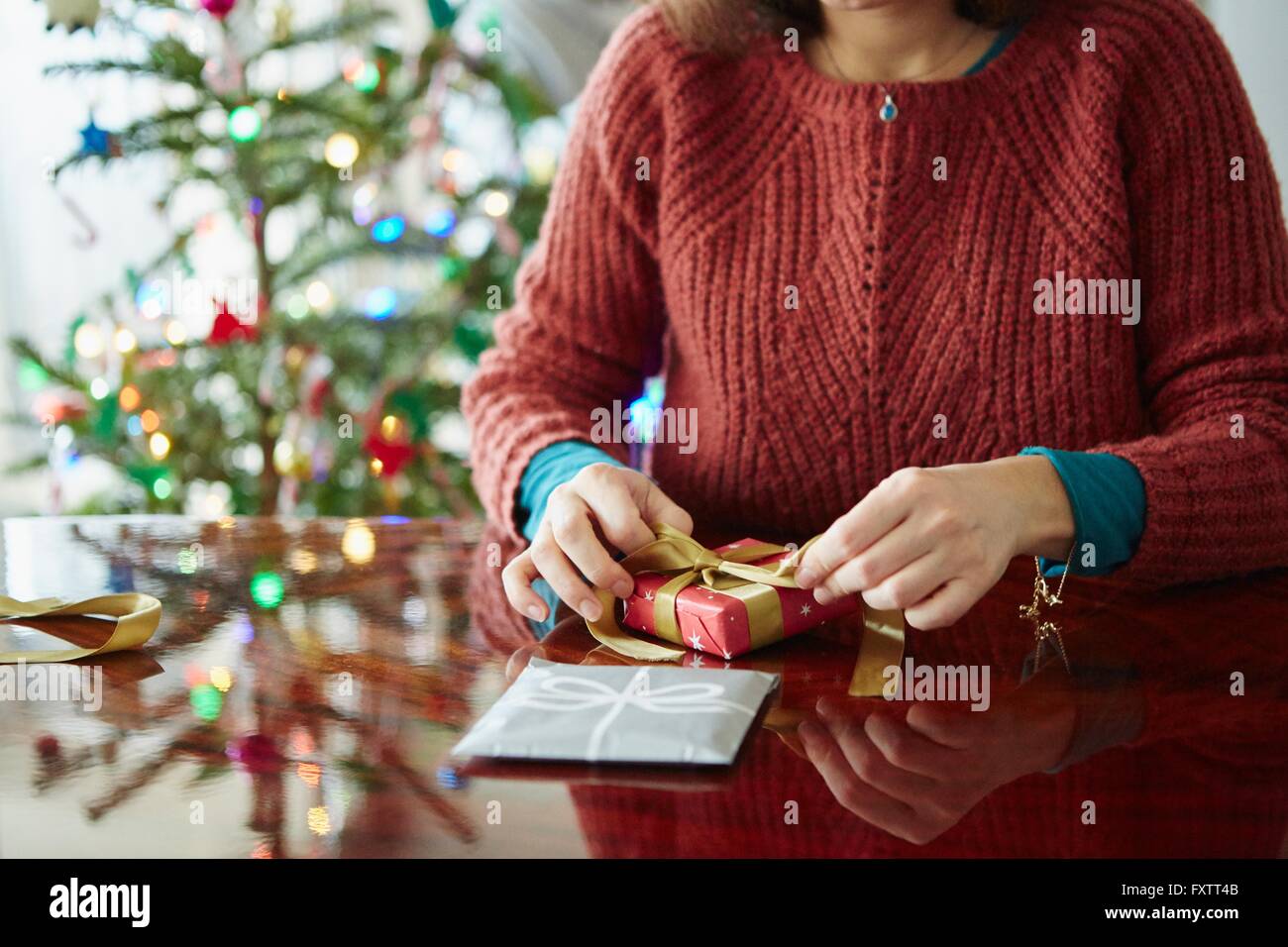Cropped shot of woman wrapping xmas gift at table Stock Photo