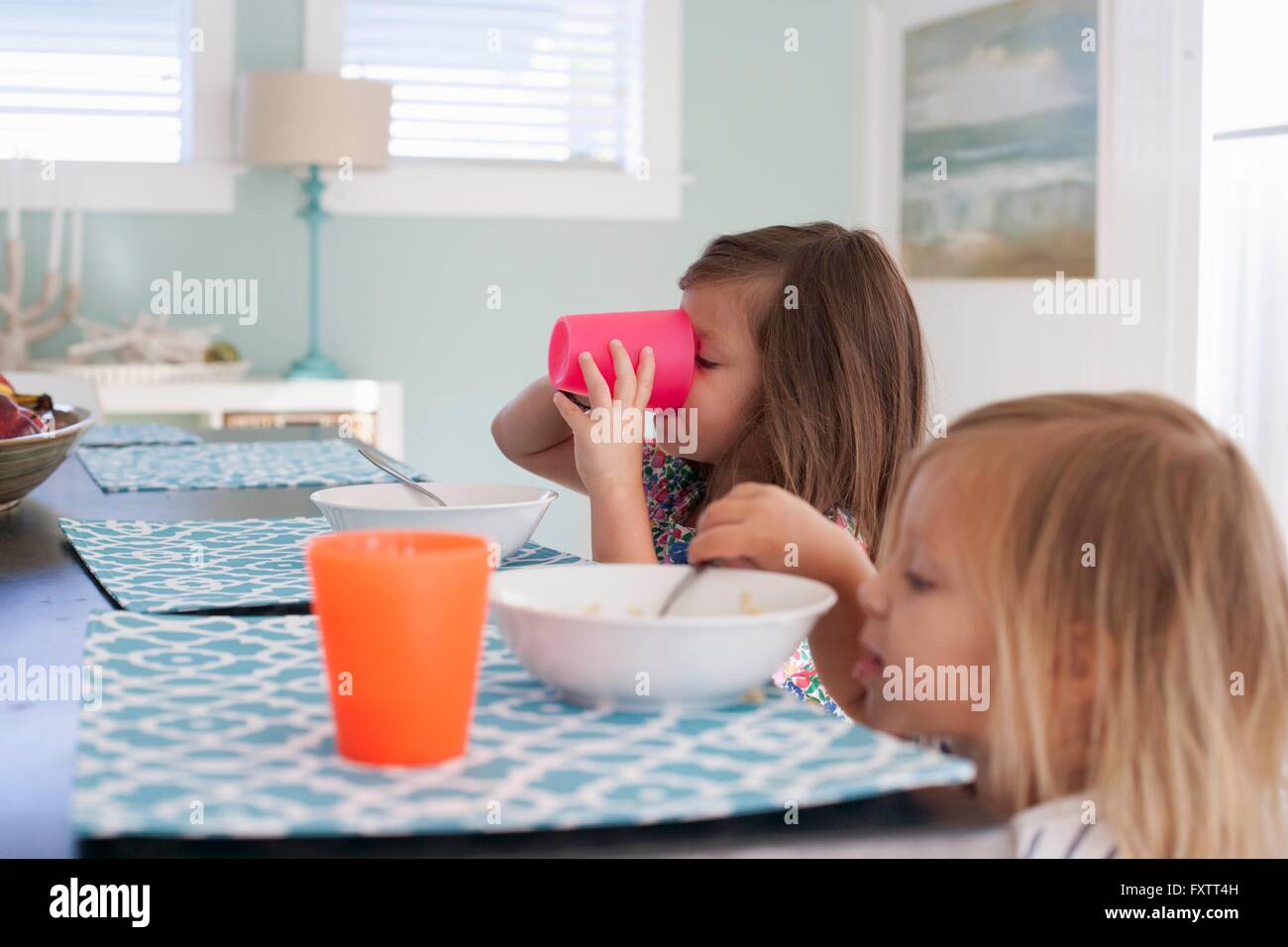 Side view of sisters at dining table eating breakfast Stock Photo - Alamy