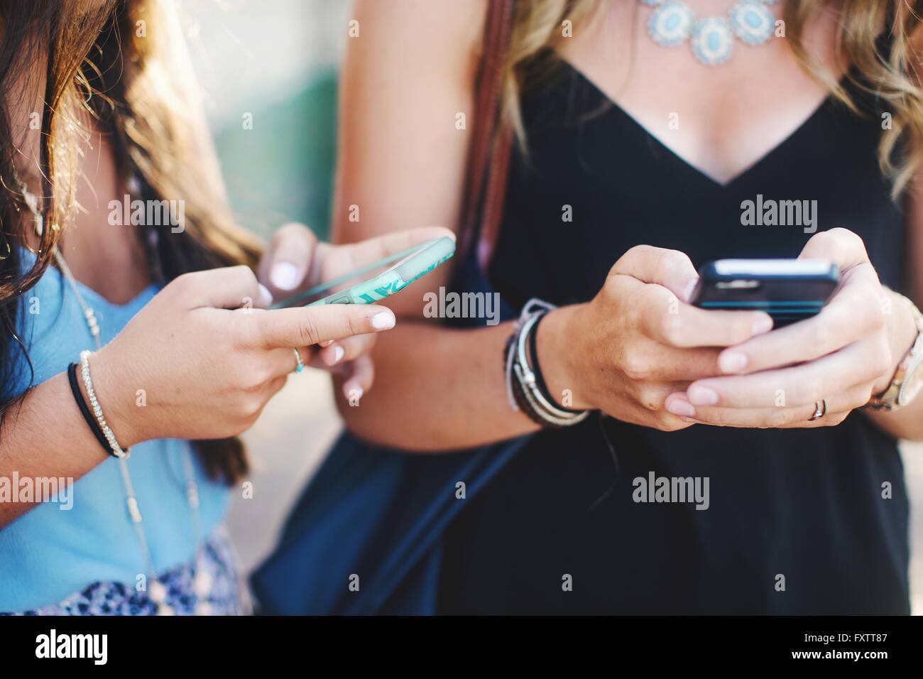 Cropped view of womens mid sections texting on smartphones Stock Photo ...