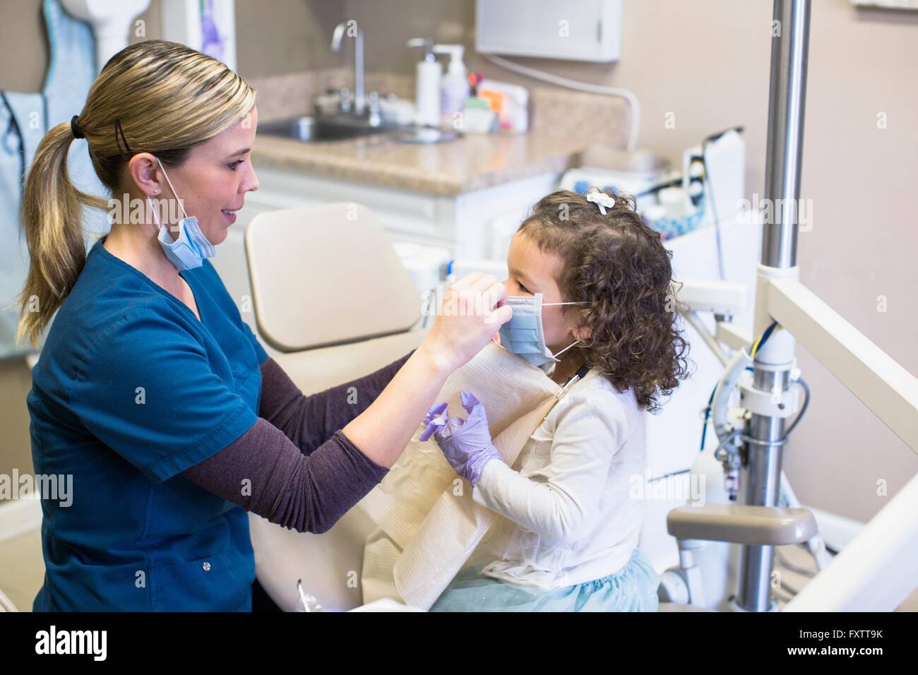 Side view of girl and dentist in dental office wearing surgical masks