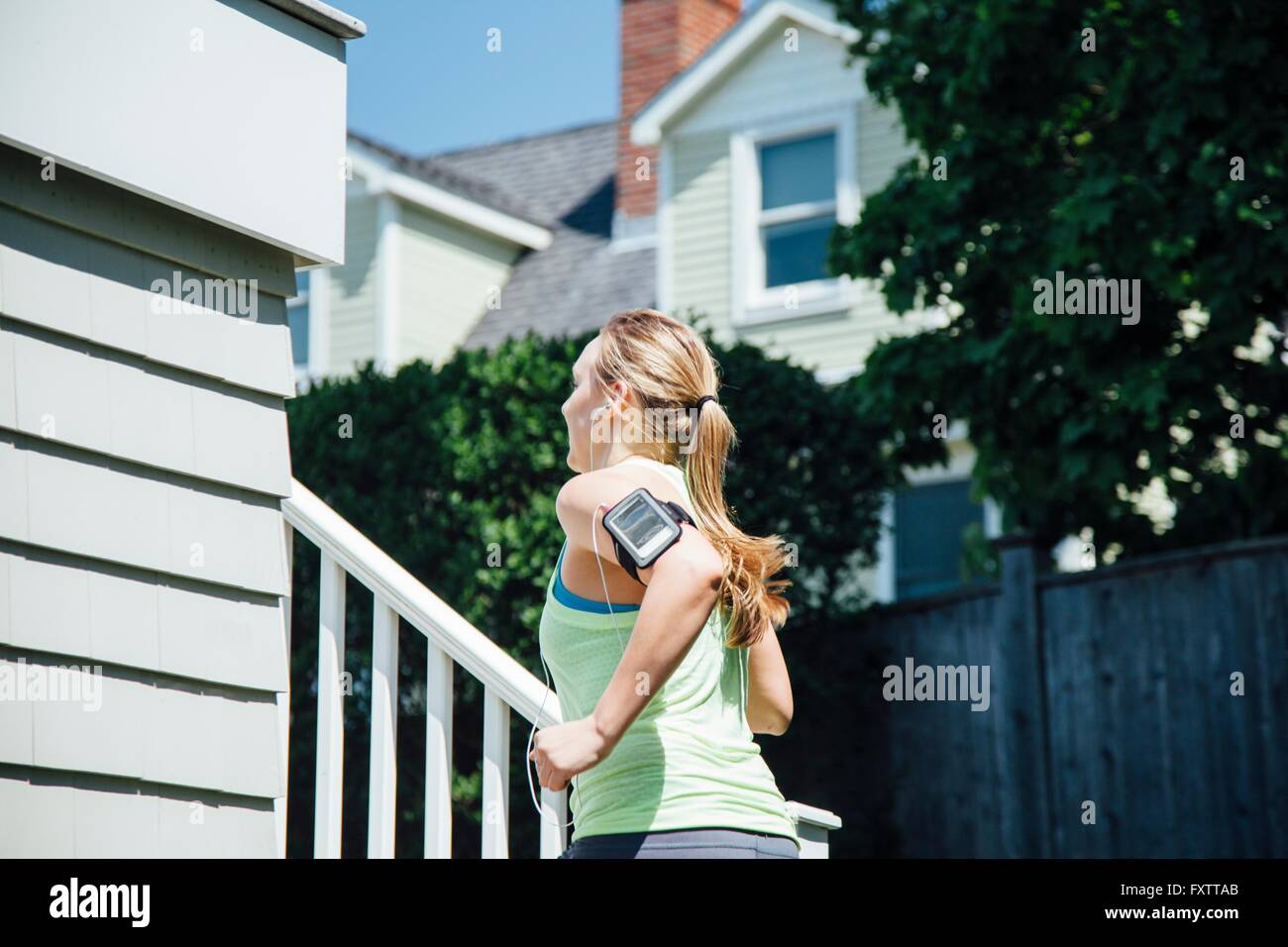 Rear view of woman wearing activity tracker running up stairs Stock Photo