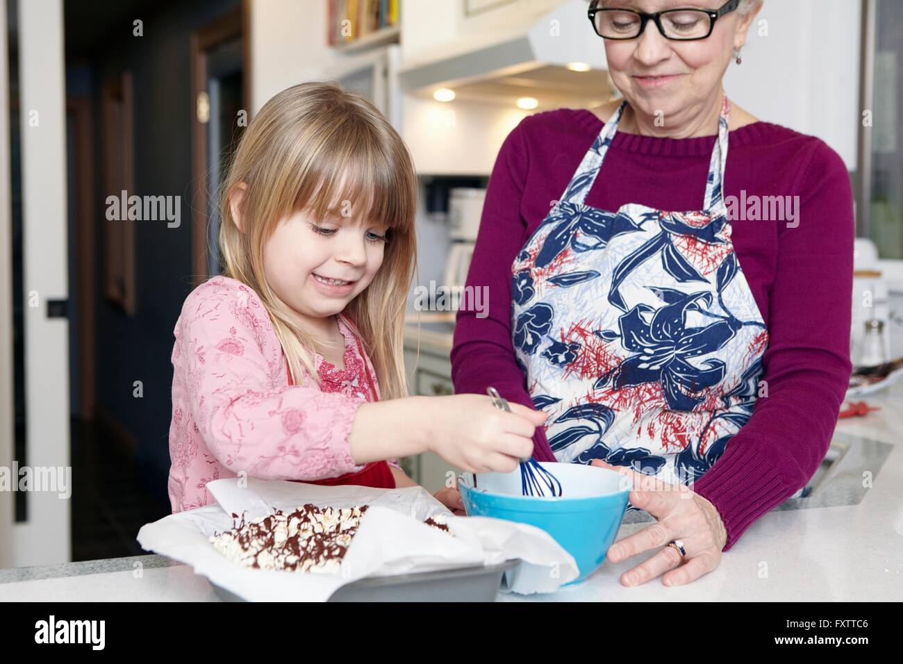Girl whisking cake at kitchen counter with grandmother Stock Photo Alamy