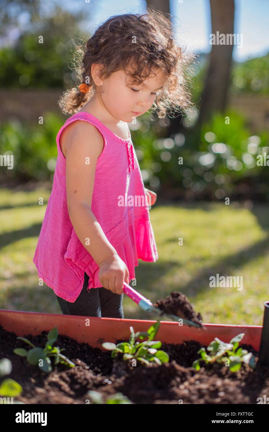Young girl in garden, digging with trowel Stock Photo