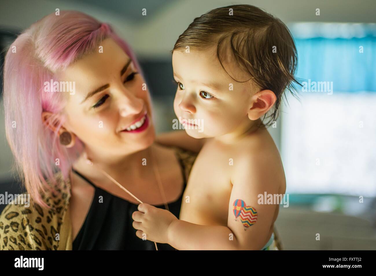 Portrait of young woman with pink hair carrying baby son Stock Photo