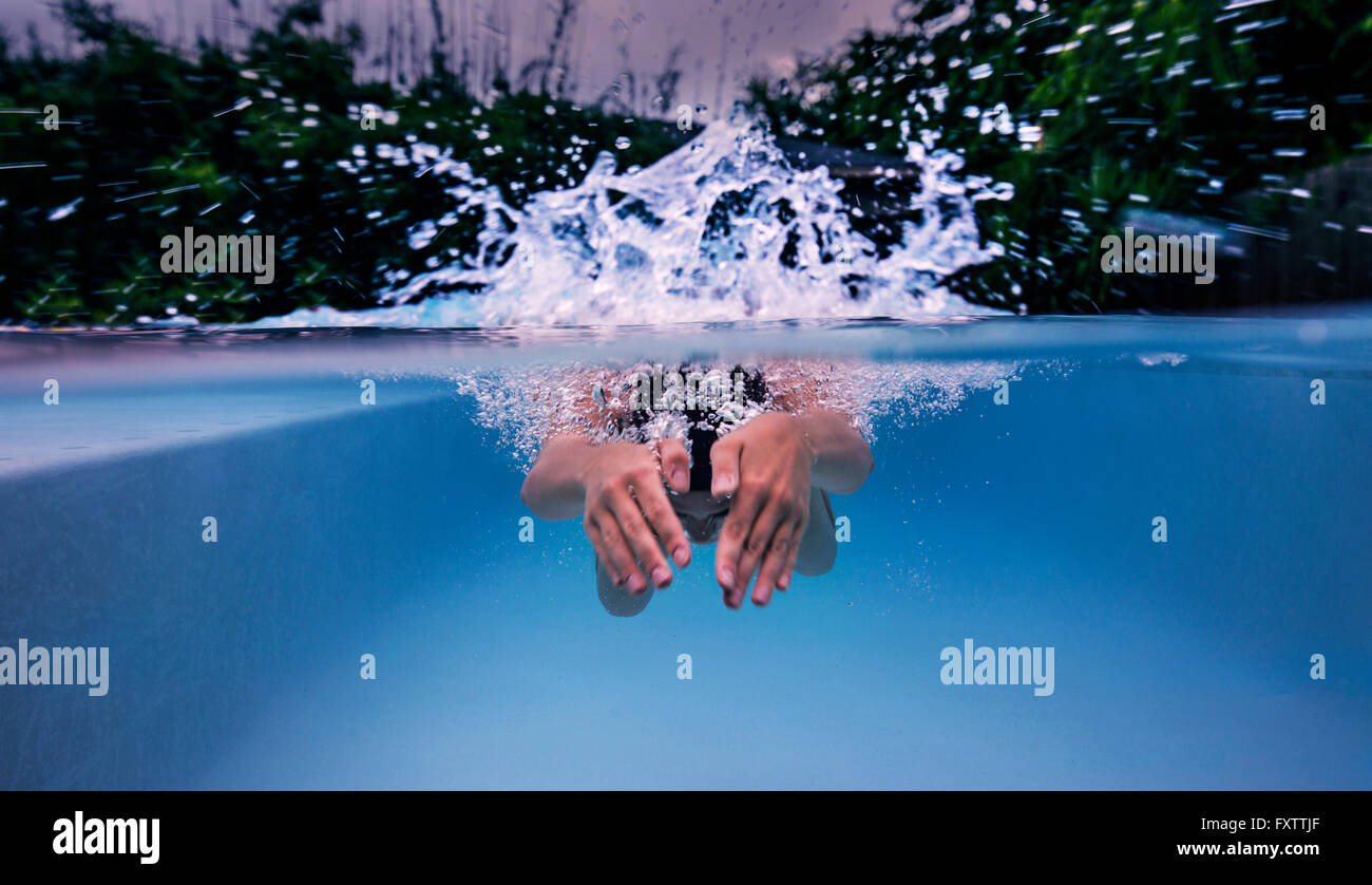Underwater view of teenage girl swimming and splashing  pool surface Stock Photo