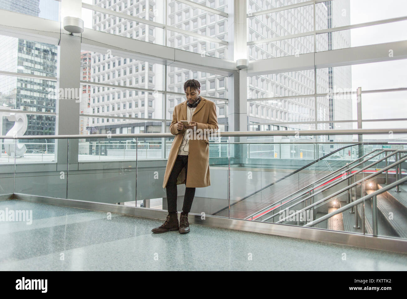 Young businessman selecting smartphone music in train station atrium Stock Photo