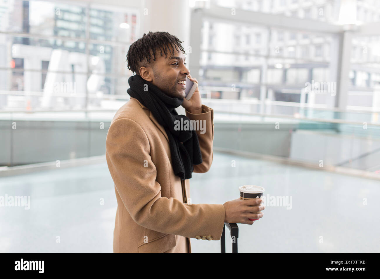 Young businessman talking on smartphone in train station atrium Stock Photo