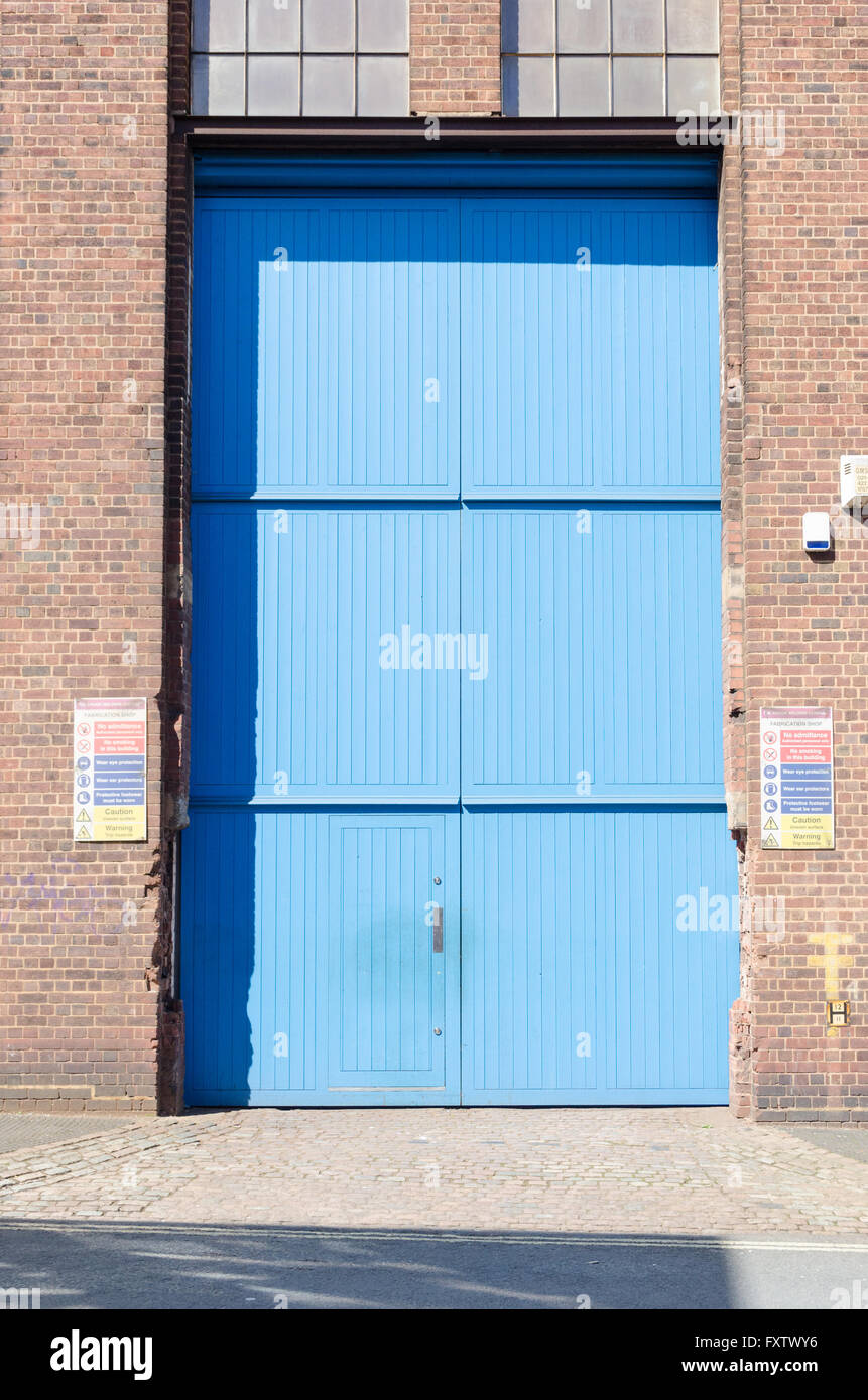 Very tall wooden garage doors at the entrance to an old bus depot in Birmingham Stock Photo