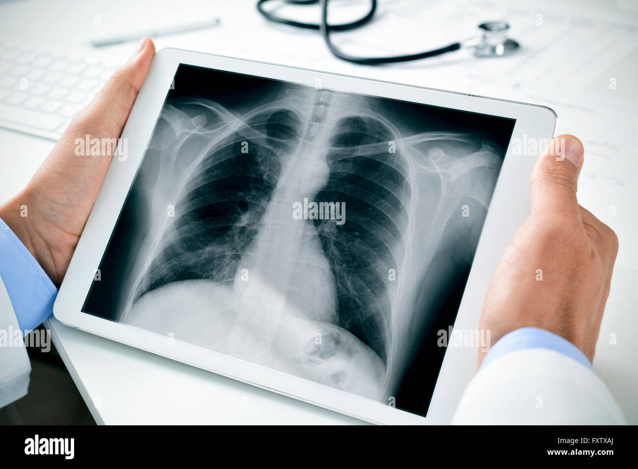 closeup of a young caucasian doctor man sitting at his office desk observing a chest radiograph in a tablet computer Stock Photo