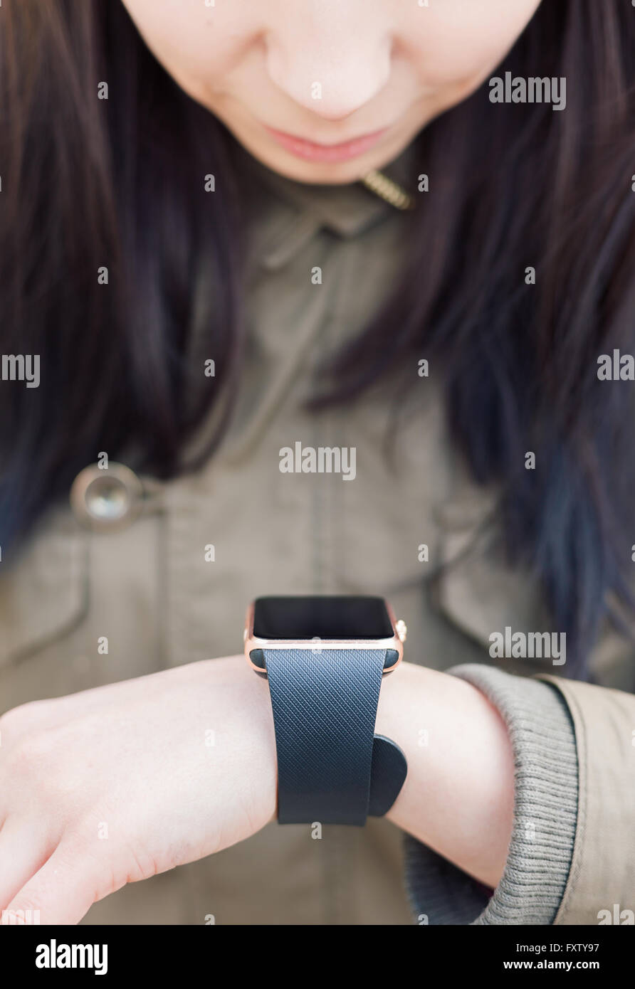 Young girl looking at her smart watch on wrist. This new gadget lets you always stay connected to internet and social media networks from anywhere you want. Stock Photo