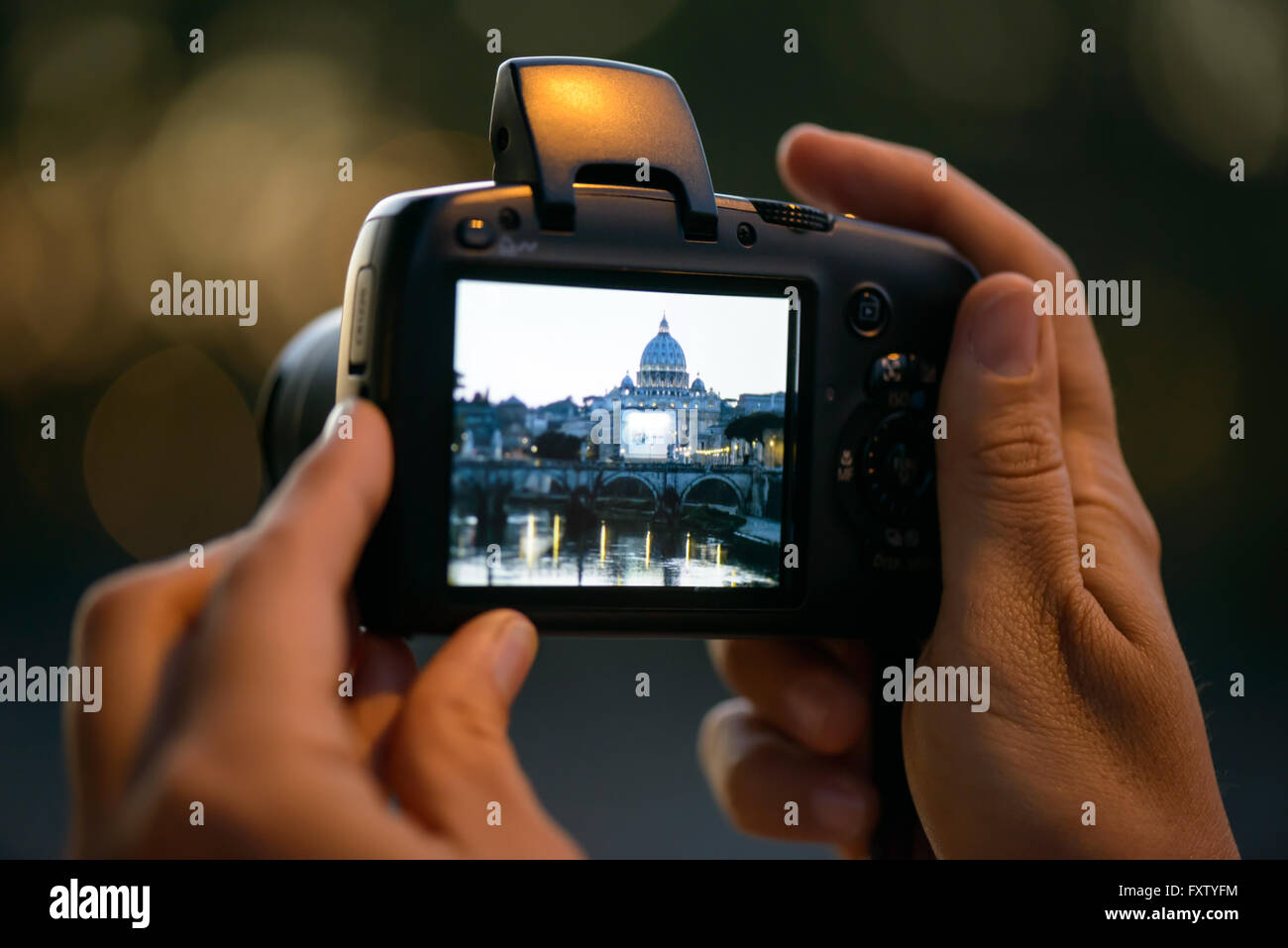 saint peter on a display of a compact camera a girl taking this photo in Rome at sunset Stock Photo