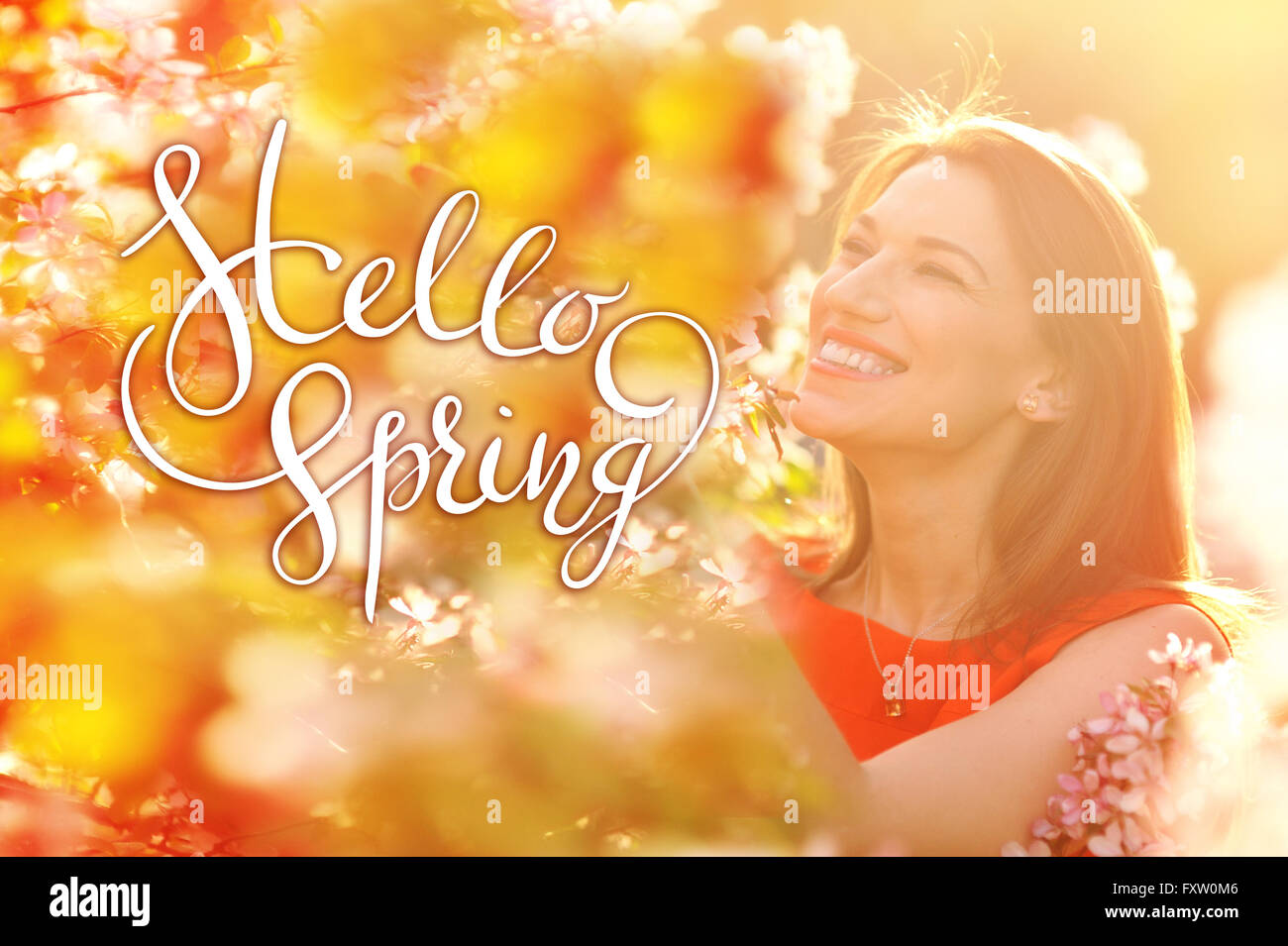 young woman enjoying smell in a flowering spring garden with letters Hello sprint Stock Photo