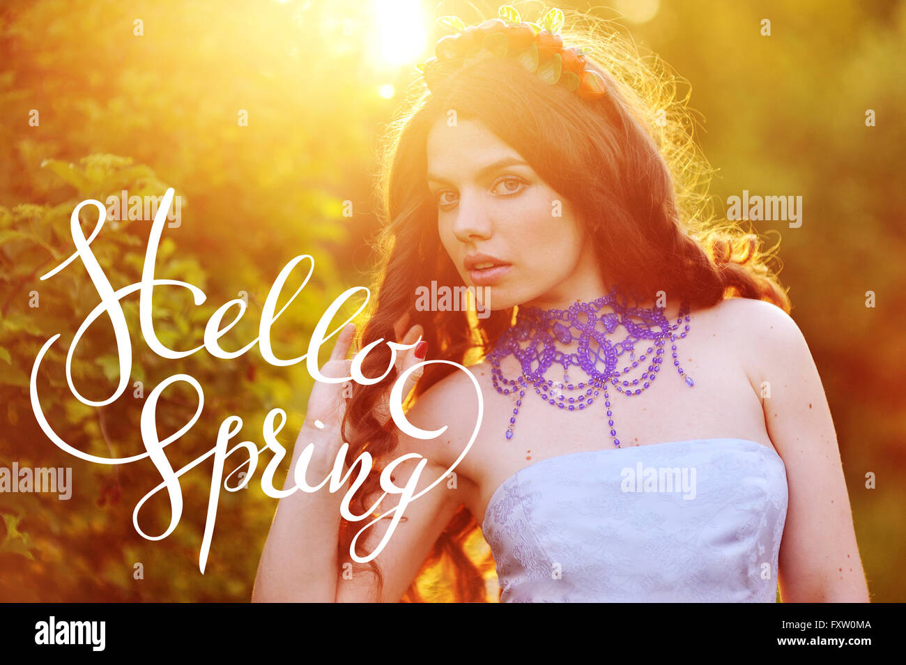 Beautiful happy young woman enjoying smell in a flowering spring garden with letters Hello sprint Stock Photo