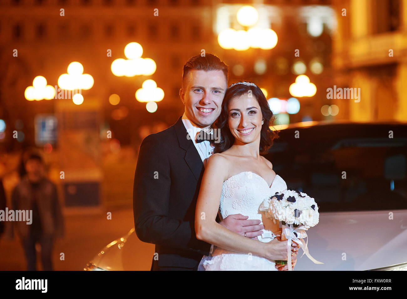 portrait bride and groom walk in city at night Stock Photo