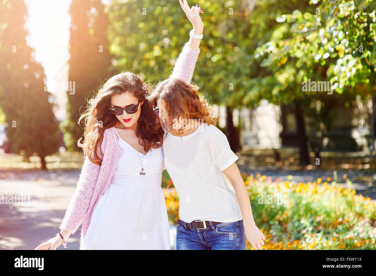 Two young happy women walking in the summer city Stock Photo