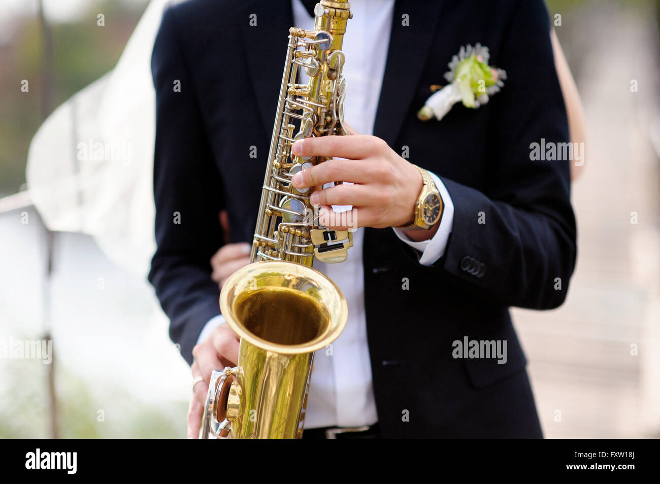 Hands of groom play on saxophone Stock Photo
