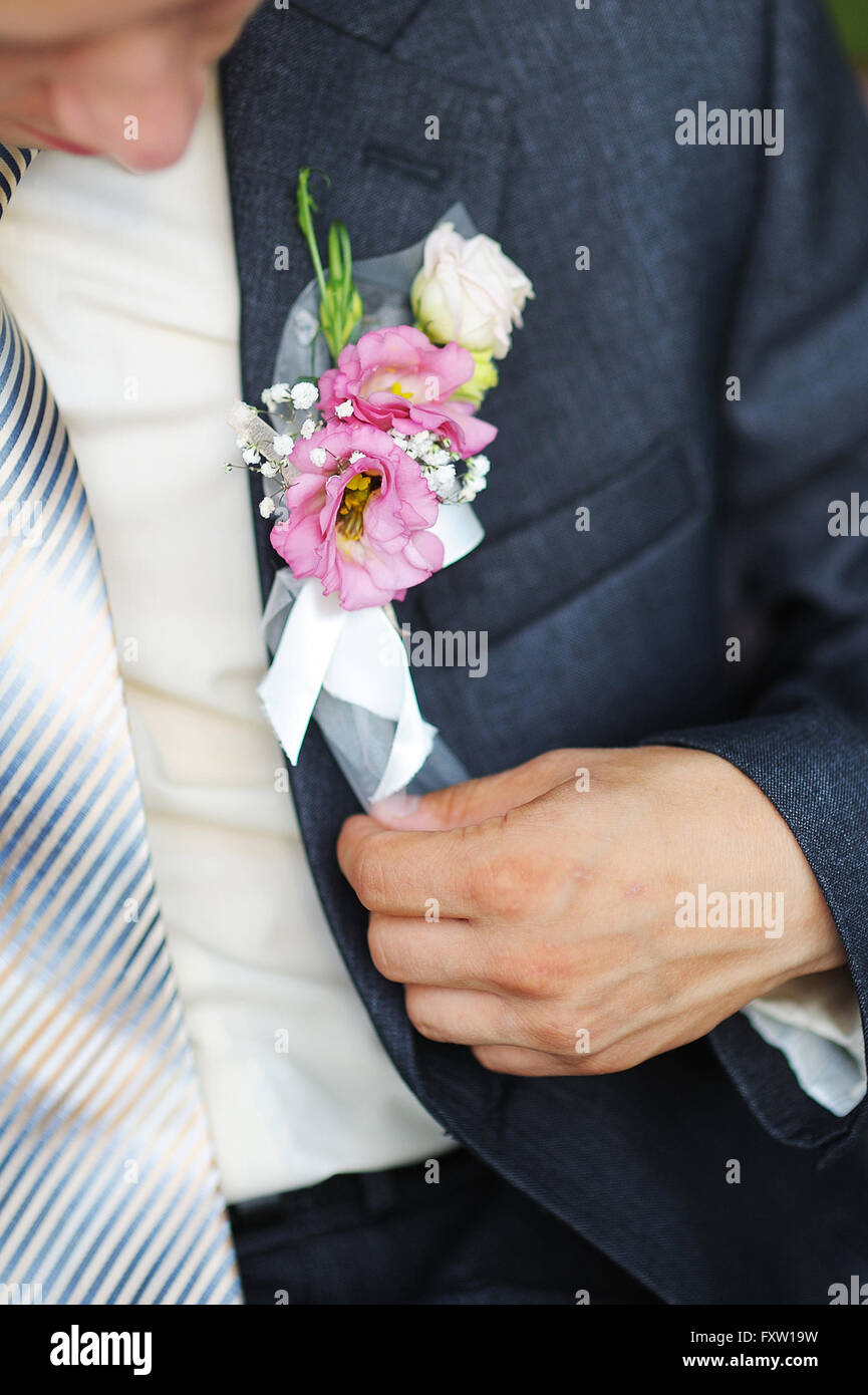 groom adjusts his boutonniere of pink flowers close up Stock Photo
