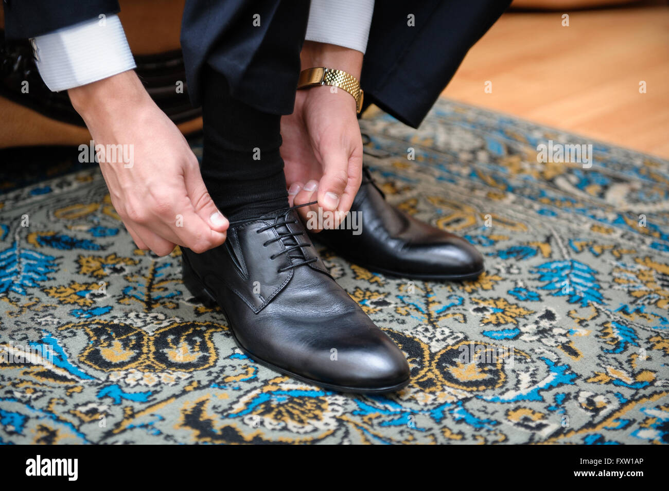 groom ties the laces on black wedding shoes Stock Photo