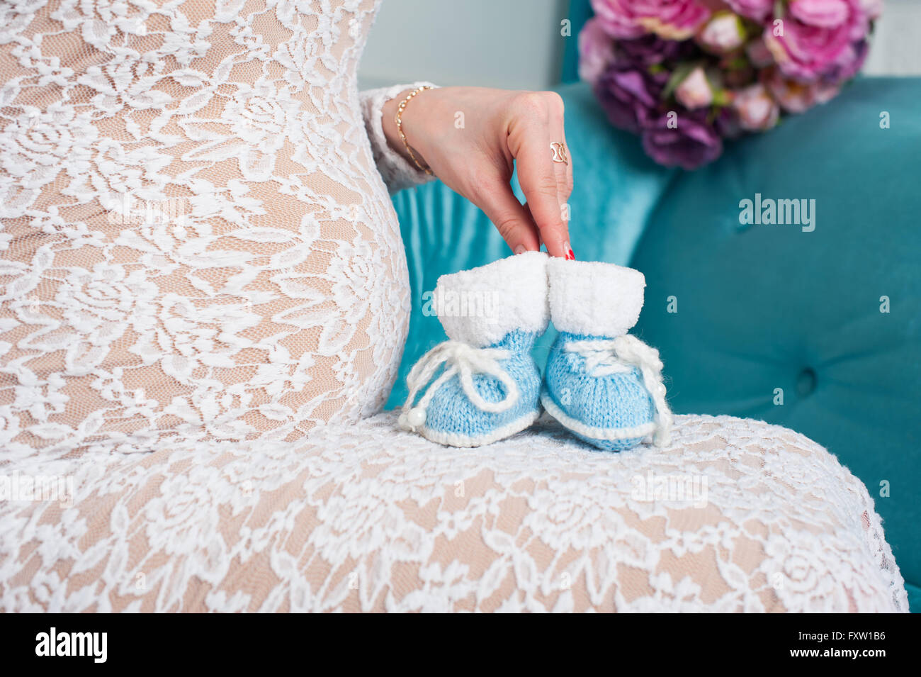 pregnant mother holding little knit baby shoes Stock Photo